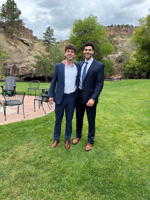 Photo of two men in suits on a lawn with a red-rock canyon behind them
